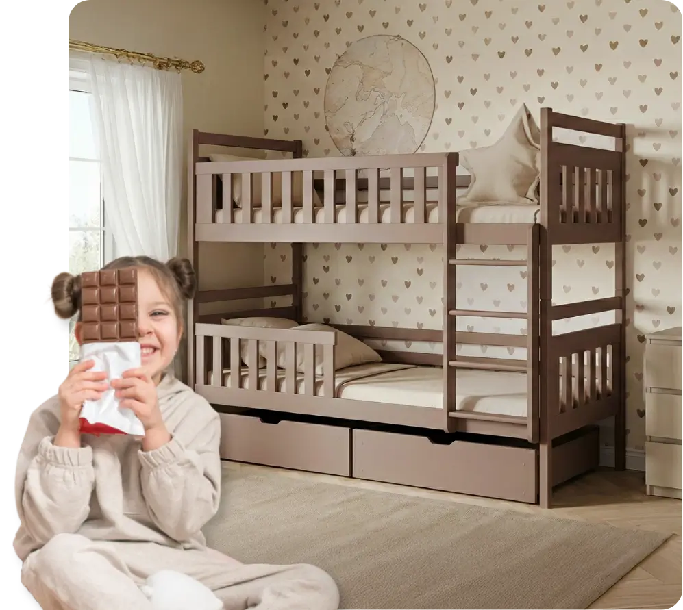 Dziewczynka siedzi uśmiechnięta z czekoladą na tle łóżka piętrowego o kolorze czekolady